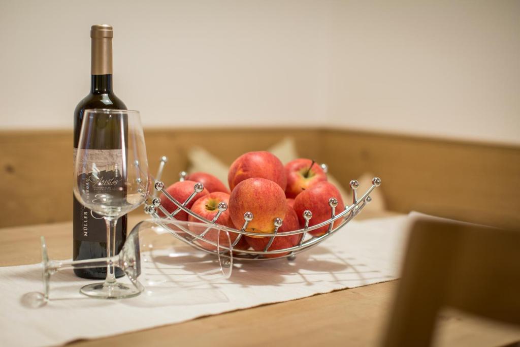 韦尔图尔诺Brugger Hof的桌上一碗苹果和一瓶葡萄酒