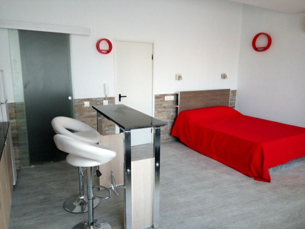 皮内达德马尔Apartamentos Bcntourism的一间卧室配有红色的床、一张桌子和一把椅子
