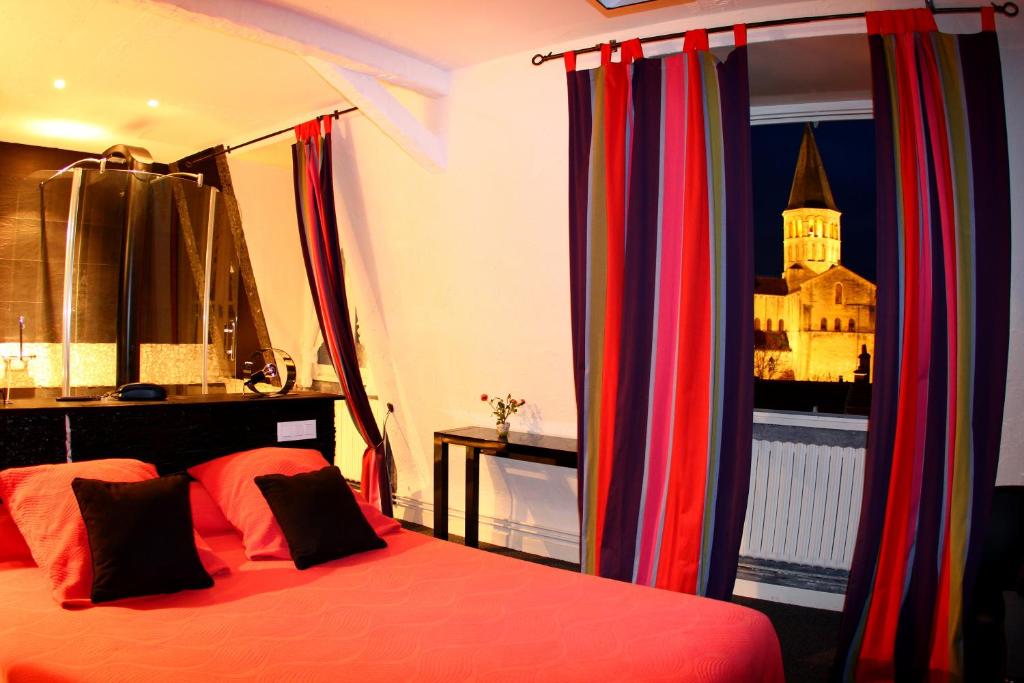 帕雷·勒·毛尼尔Hotel de la Basilique的一间卧室配有一张带色彩缤纷窗帘的床和窗户。