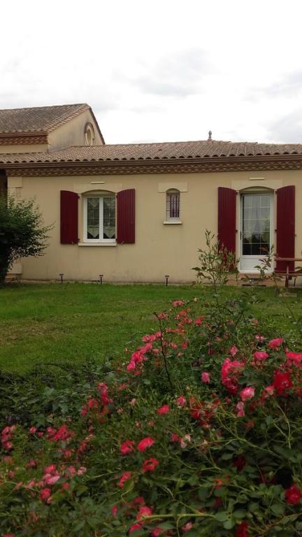 GinestetMaison d'Hôtes Afrika du Queyroux的院子里有红色百叶窗和鲜花的房子