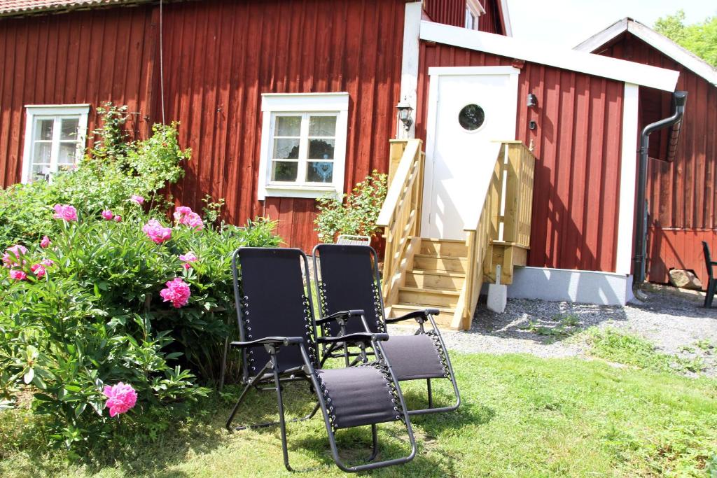 科尔莫登Kolmårdstorpet Blomsätter的两把椅子坐在红色建筑前面