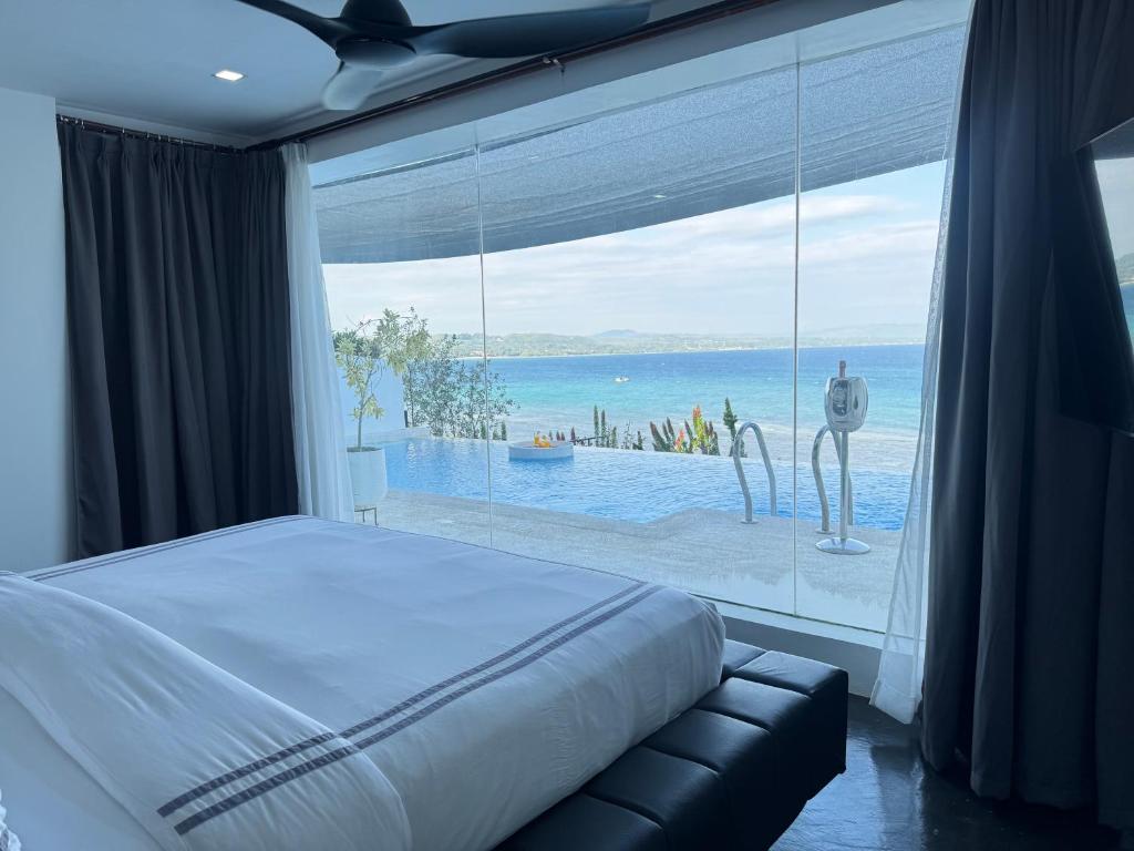 道伊斯Epic Suites Bohol ADULTS ONLY的一间卧室，有一扇大窗户，可以看到海景