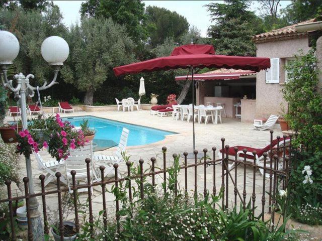 胡安莱潘Villa l'Air du temps的一个带红色遮阳伞和桌椅的游泳池