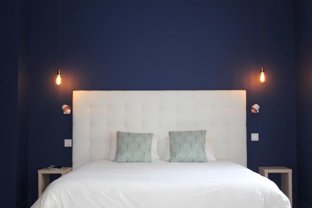凯恩福恩塔尼卡昂中心酒店的一间卧室配有白色的床和2个蓝色枕头
