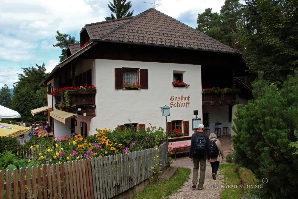 索普拉布扎诺Gasthof Schluff的男人和女人在房子前面走