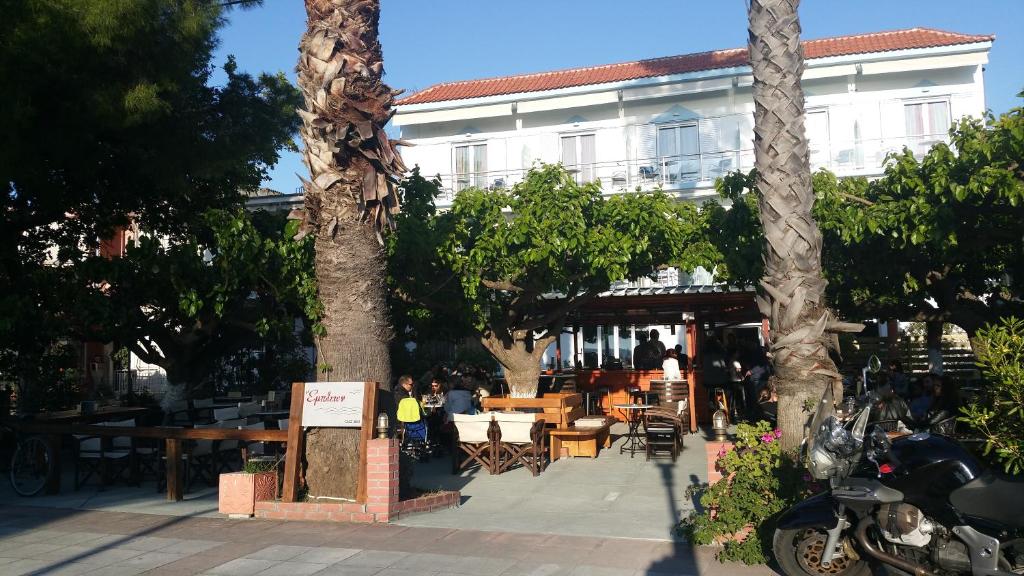 佩弗奇Mirtia Hotel的一间设有桌椅和树木的餐厅,以及一座建筑