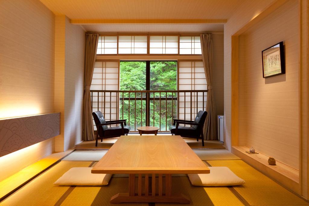 会津若松庄助の宿瀧の湯日式旅馆的客房设有桌椅和窗户。