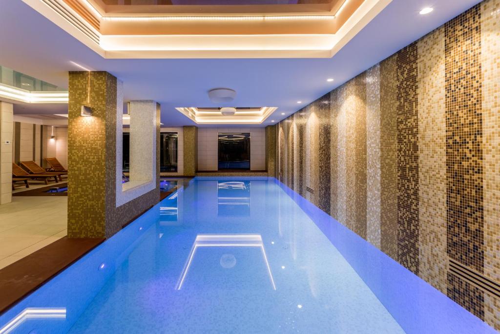 马马亚新辉煌酒店及Spa - 仅限成人（16岁以上）的一座位于酒店带瓷砖墙的游泳池