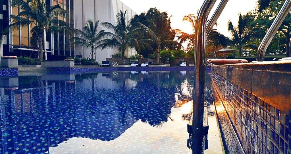 金沙萨Fleuve Congo Hotel By Blazon Hotels的一座棕榈树游泳池和一座建筑