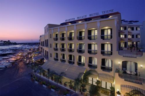 伊斯基亚亚拉贡宫温泉酒店的酒店大楼的背景是海滩