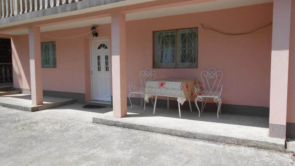 科托尔Apartment and Rooms Novka的粉红色的房子,配有两把椅子和一扇门