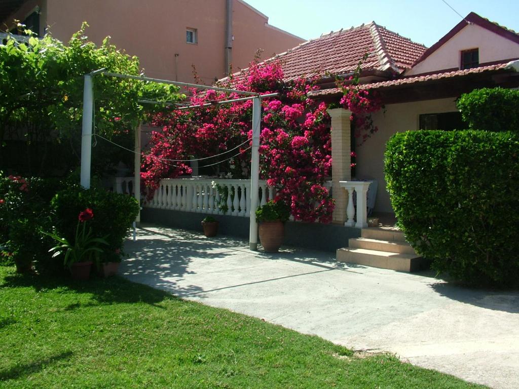 圣斯特凡诺斯Spiridoula apartments的一座粉红色花卉和白色围栏的房子