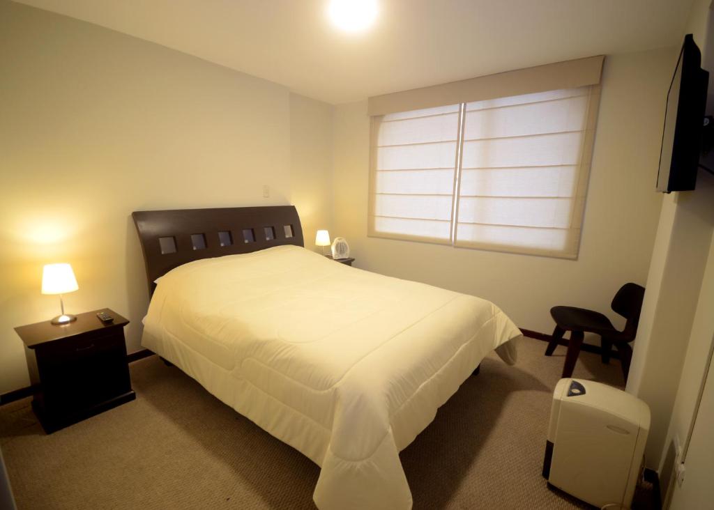 利马Luxury Apartments Miraflores的卧室配有白色的床和窗户。