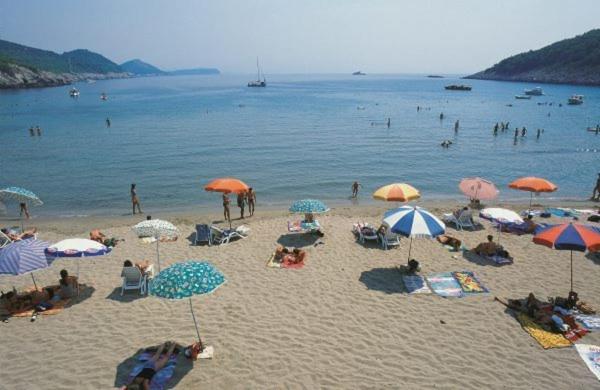 洛帕德Villa Franka的一群人在海滩上,带遮阳伞