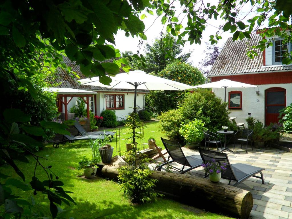 DegnbølLille Degnbøl Holiday House的花园配有桌椅和遮阳伞
