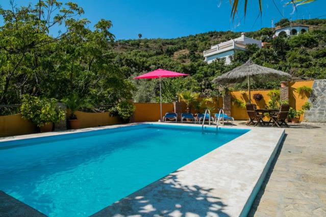 内尔哈Finca El Valle的一个带遮阳伞和桌椅的游泳池