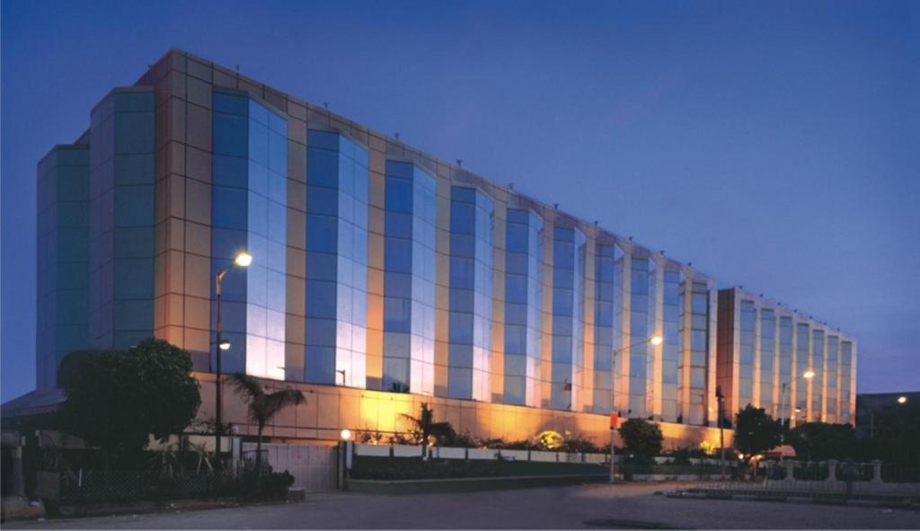孟买Ramada Plaza By Wyndham Palm Grove的一座大型建筑,晚上设有反射窗