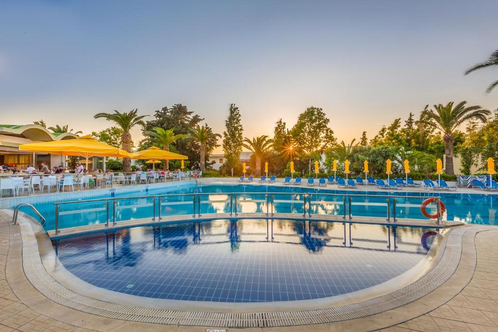 科斯镇Kipriotis Hippocrates Hotel的一个带桌椅的度假村游泳池