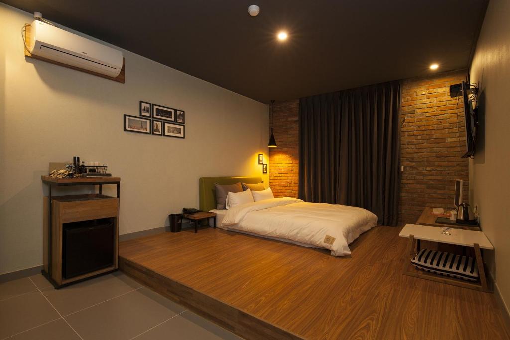 昌原市格雷酒店的一间卧室设有一张床和砖墙