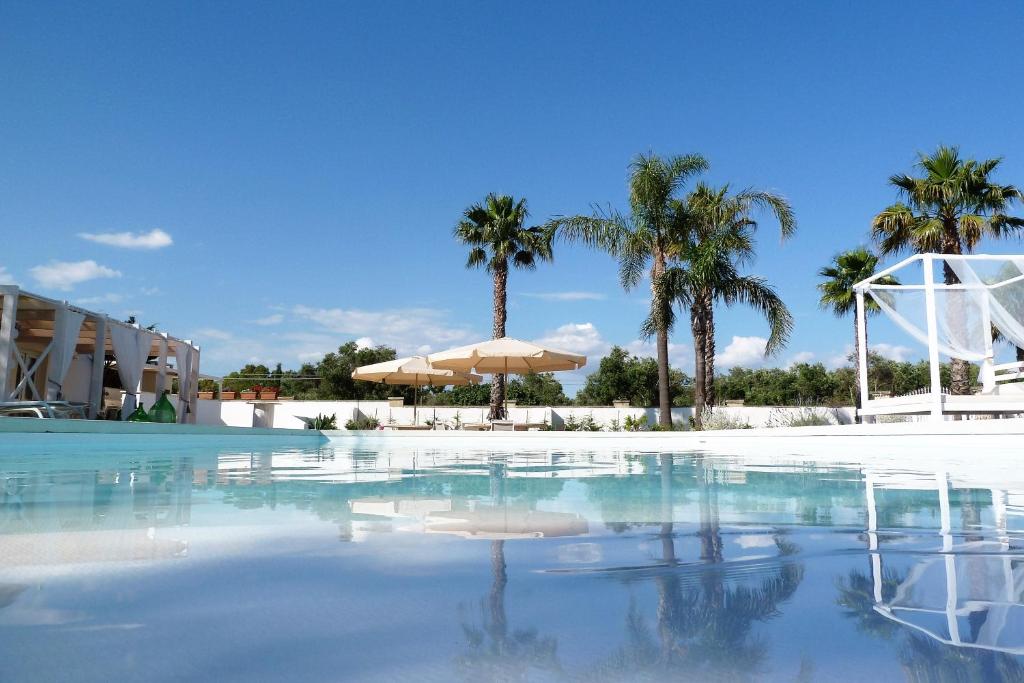 托雷圣乔万尼乌Giardino TerraNostra的一座拥有棕榈树和遮阳伞的游泳池