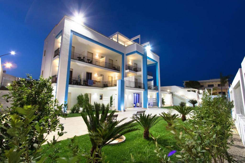 佩斯科勒海滨Gigli Hotel Salento的白色的大建筑,晚上有蓝色的点缀
