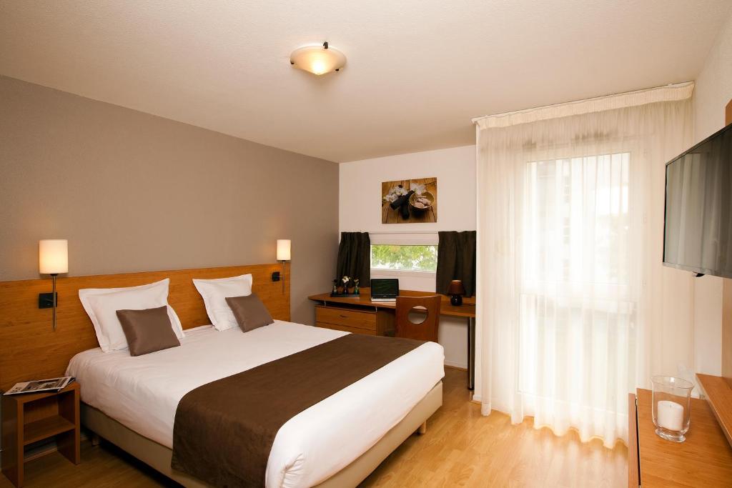 拉罗谢尔罗谢尔米尼姆公园和套房酒店的酒店客房设有床和窗户。