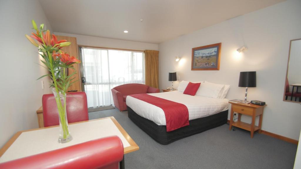 基督城ASURE Christchurch Classic Motel & Apartments的配有一张床和花瓶的酒店客房