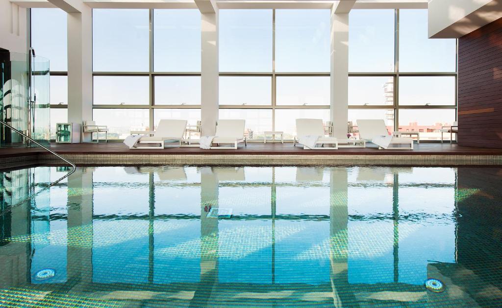 萨拉戈萨佩德罗尼拉女王酒店的一座带白色躺椅的游泳池