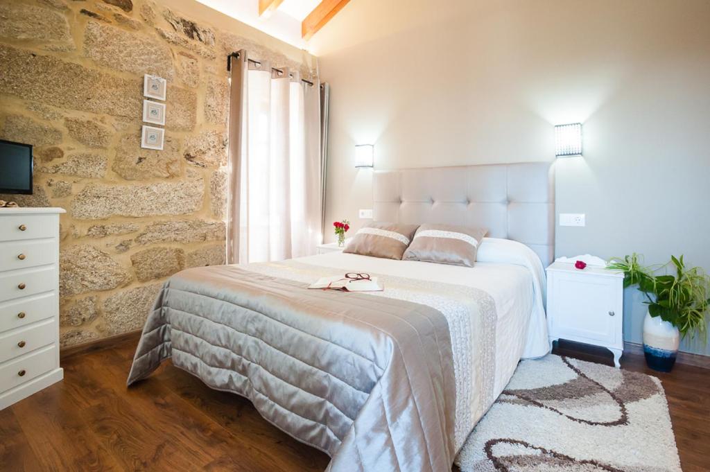 蒙达里斯A Cantaruxa Maruxa Turismo Rural的卧室配有一张白色的大床和石墙