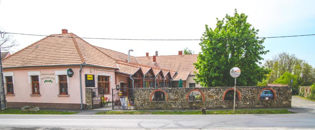 SitkeBorostyánkert Étterem & Vendégház的一条街道旁的粉红色房子,有石墙