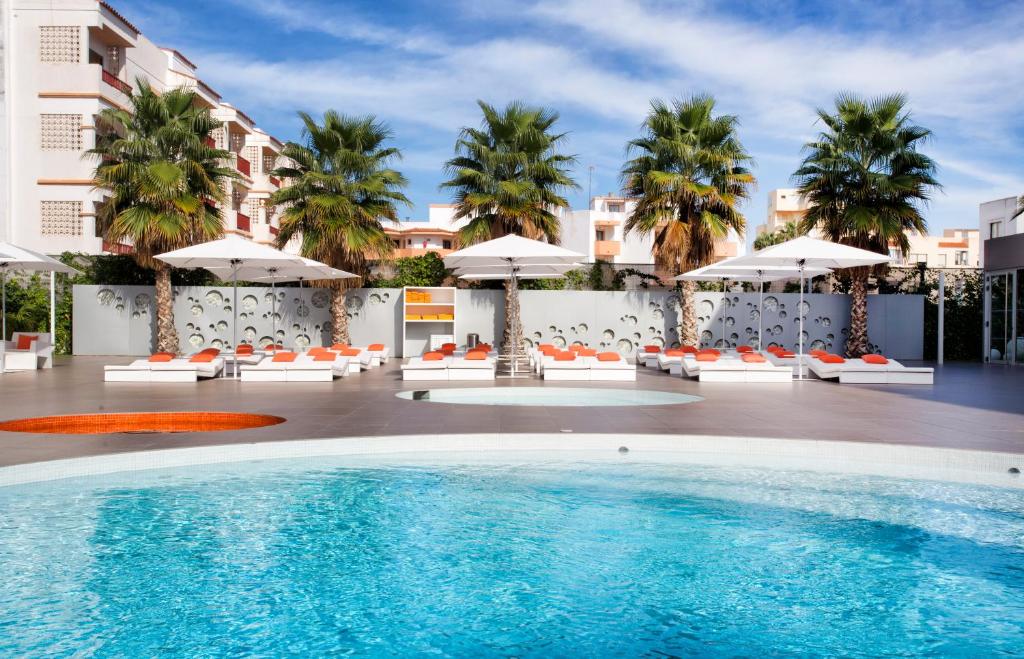普拉亚登博萨伊维萨太阳公寓酒店的一个带遮阳伞和椅子的酒店游泳池