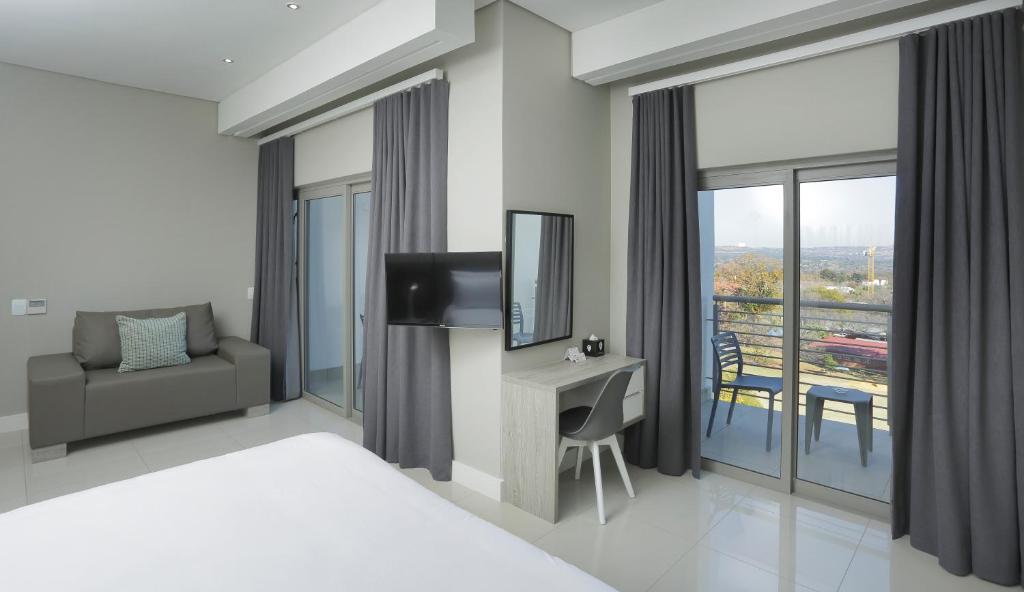 约翰内斯堡巴斯卡皮特尔公寓式酒店的一间卧室配有一张床和一张书桌及电视