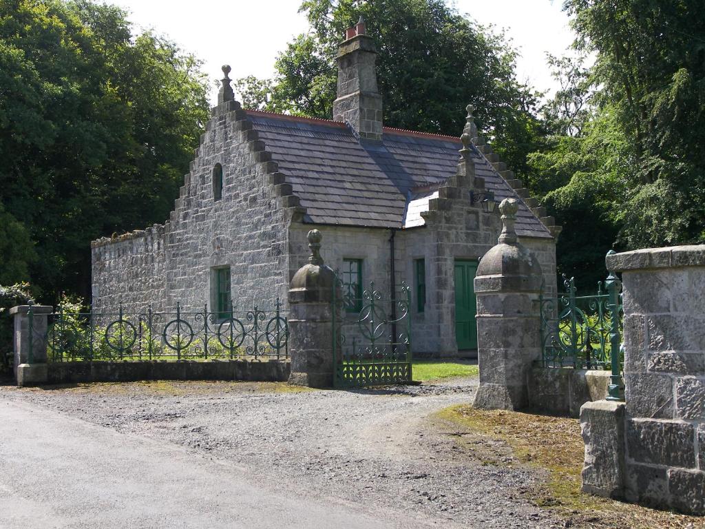 巴利卡斯尔Magherintemple Lodge的一座古老的石头房子,前面设有大门