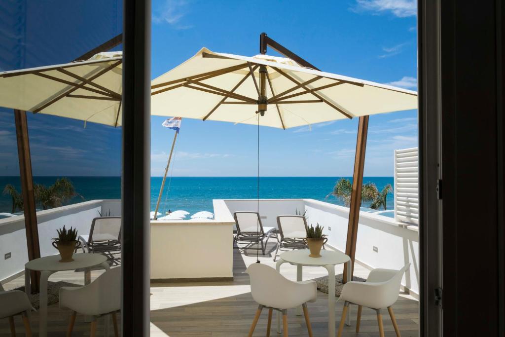 拉蒂纳米拉马雷酒店的庭院配有白色的桌椅和遮阳伞。