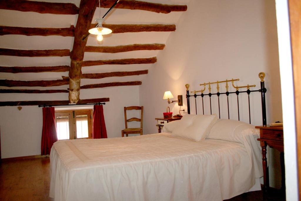 Mahora马约拉之家酒店的卧室设有白色的床和木制天花板。