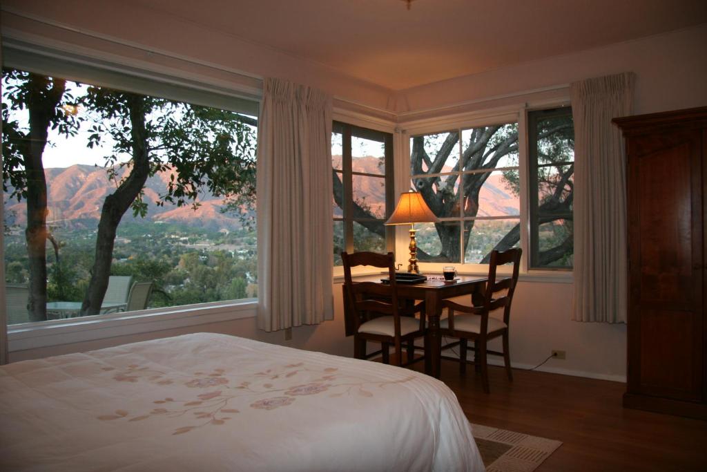 奥海Ojai Retreat & Inn的一间卧室配有桌椅和大窗户