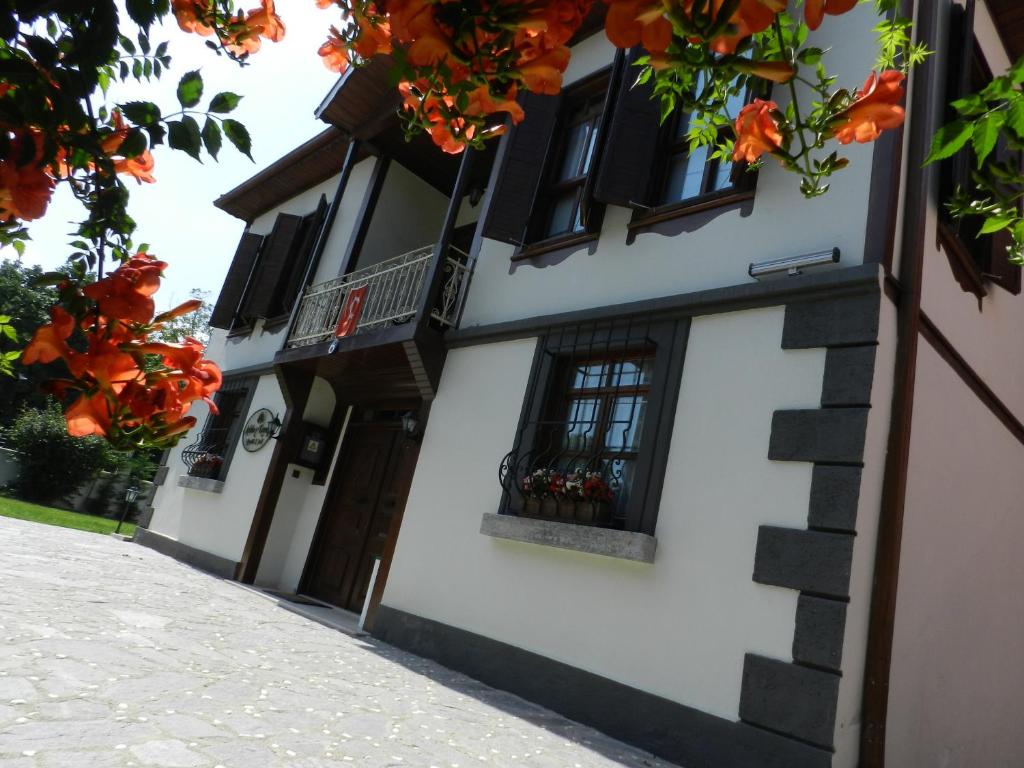 萨潘贾阿斯里贝可纳吉旅馆 - 仅限成人的白色的建筑,有黑色的窗户和橙色的鲜花