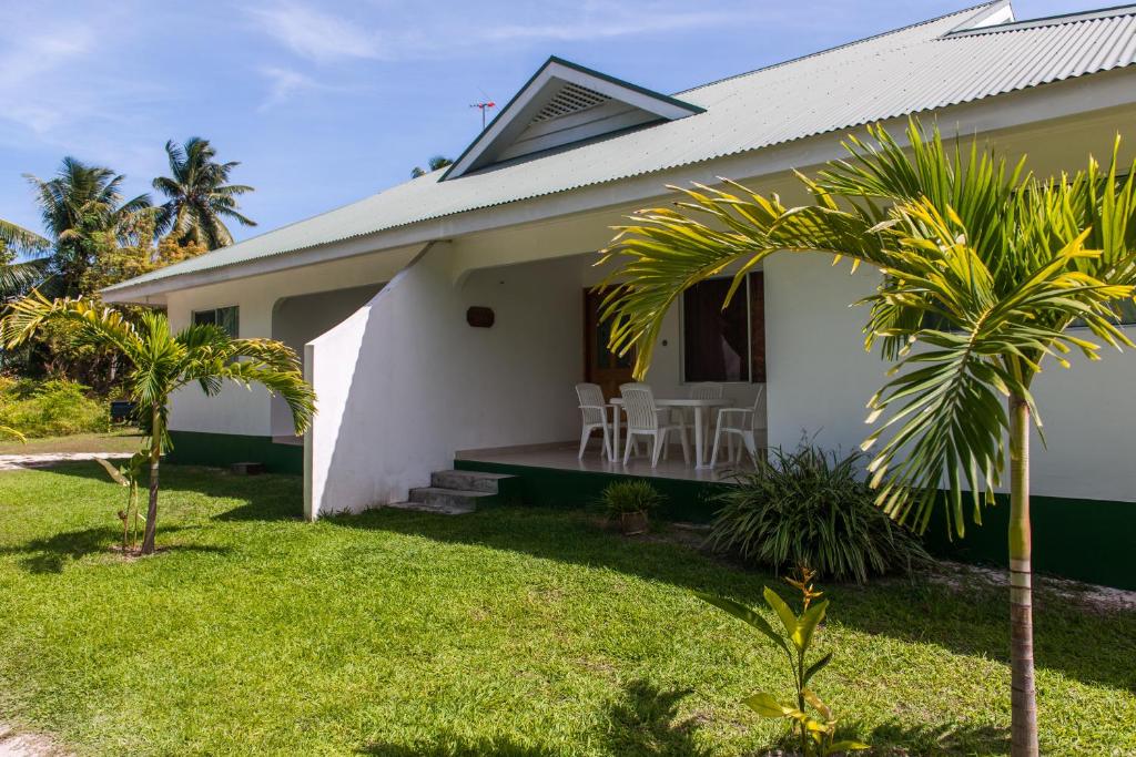 Anse Kerlan理念别墅的一座白色的房子,拥有绿色的院子和棕榈树
