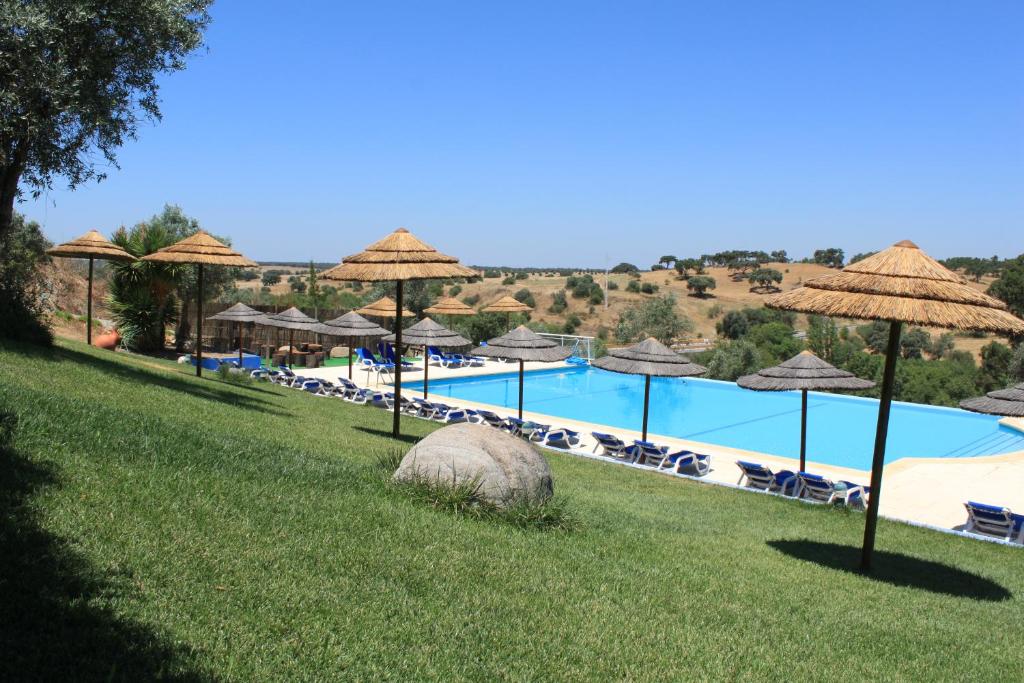 奥迪韦拉什Hotel O Gato & Spa的一个带遮阳伞和椅子的大型游泳池和一个游泳池