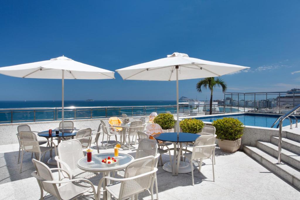 里约热内卢Windsor Palace Copacabana的一个带桌子和白色遮阳伞的庭院和大海