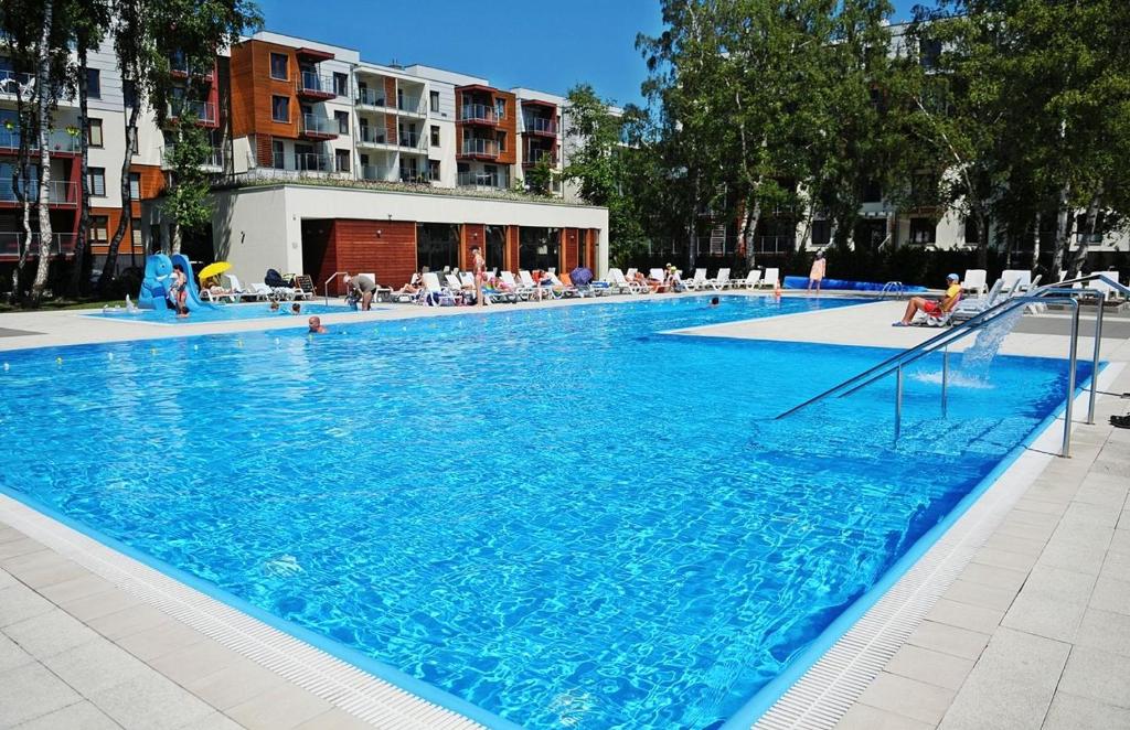 科沃布热格Apartamenty BalticON Polanki的一个大型蓝色游泳池,周围的人坐在游泳池周围