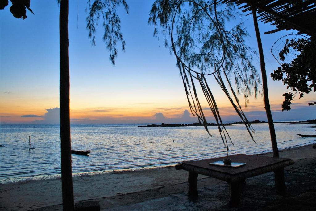 Haad Chao Phao哈超帕度假村的海滩上的长凳,背景是日落