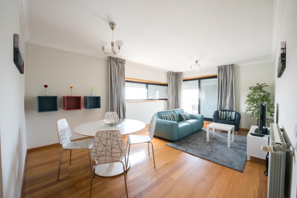 马托西纽什波尔图河海码头公寓的客厅配有桌子和蓝色沙发