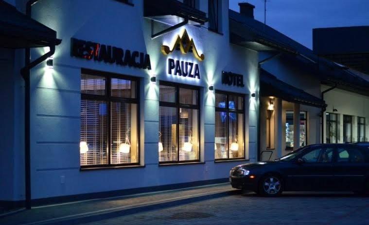 波德拉谢地区拉曾Hotel Pauza的夜间在比萨饼店前停车