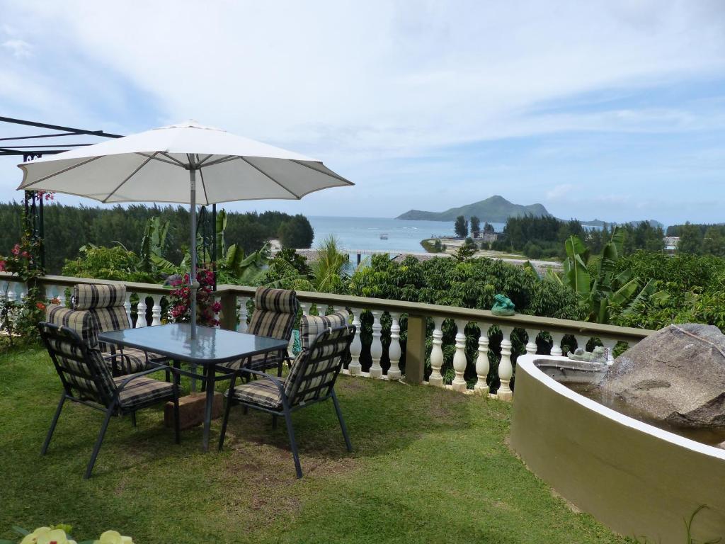 维多利亚Hibiscus House Seychelles Self Catering的一张桌子和椅子,配有雨伞和大海