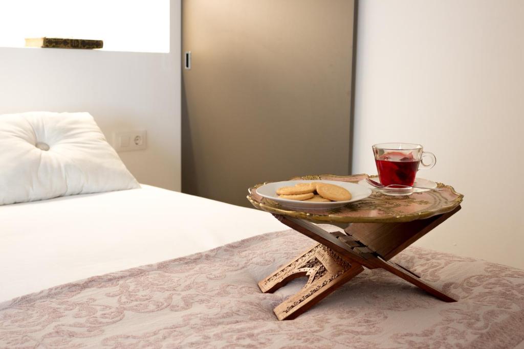 哈隆Casa Grimalt的一张盘子,上面放着饮料和饼干,放在床边的桌子上