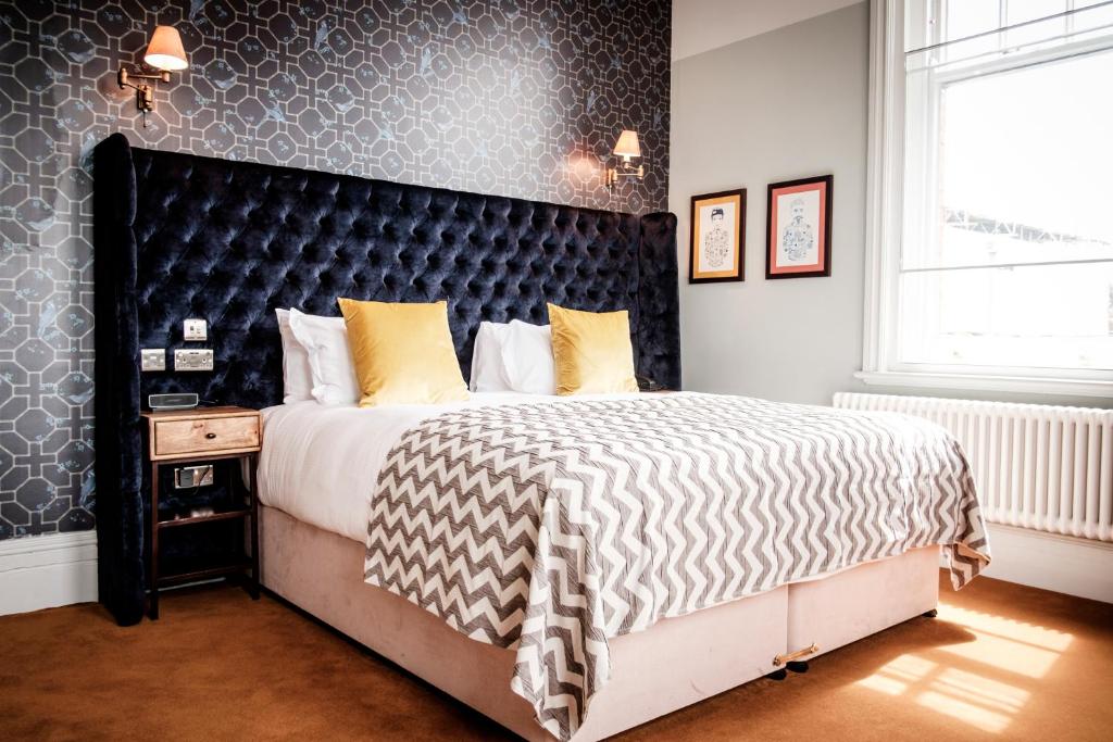 泰晤士河畔金斯顿昆世海德酒店的一间卧室配有一张大床和黑色床头板