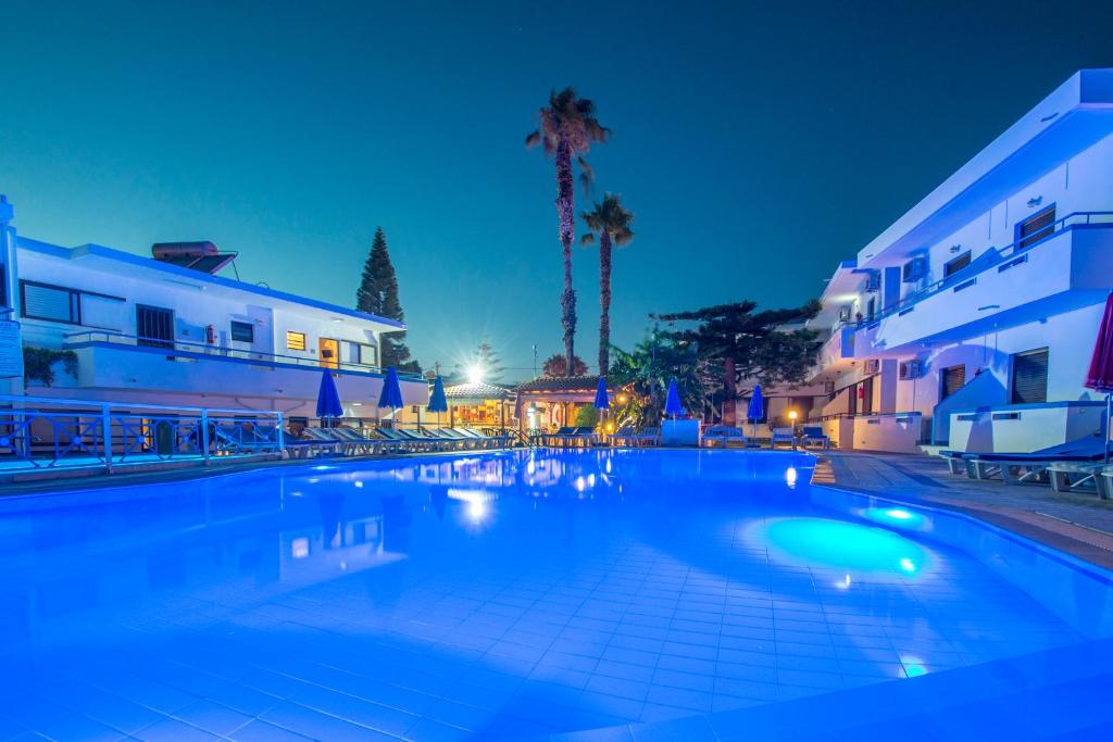 科斯镇雅尼斯庭院套房公寓的一座大型游泳池,在晚上在建筑前