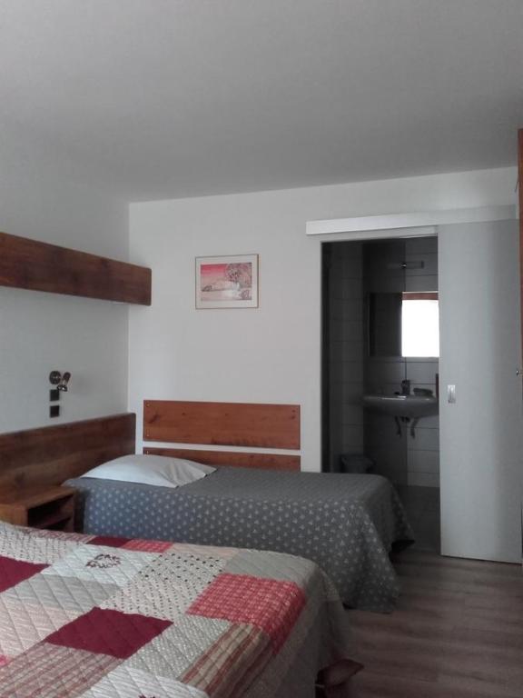 欧丹库尔杜汝拉酒店的一间带两张床的卧室和一间带水槽的浴室