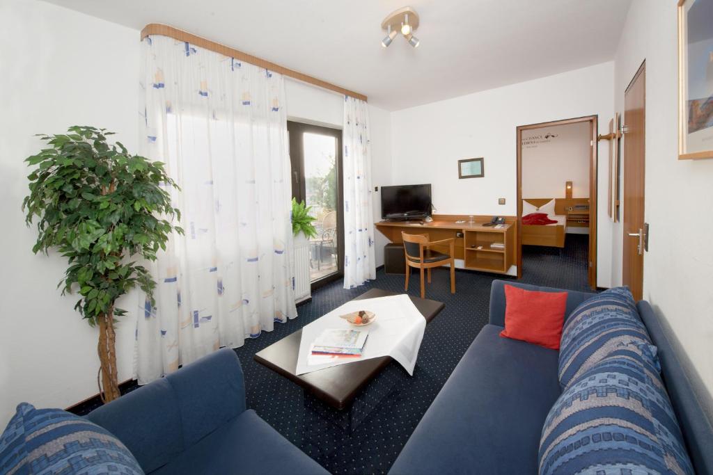 美茵河畔哈瑙哈瑙城市酒店的客厅配有蓝色的沙发和桌子